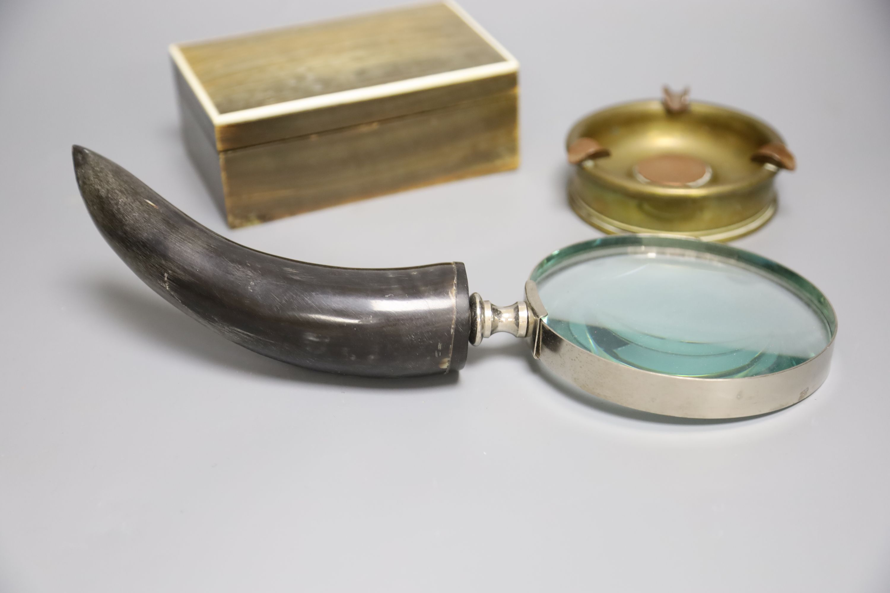 A horn veneered cigarette box, a horn handled magnifying glass and a Trench art ashtray